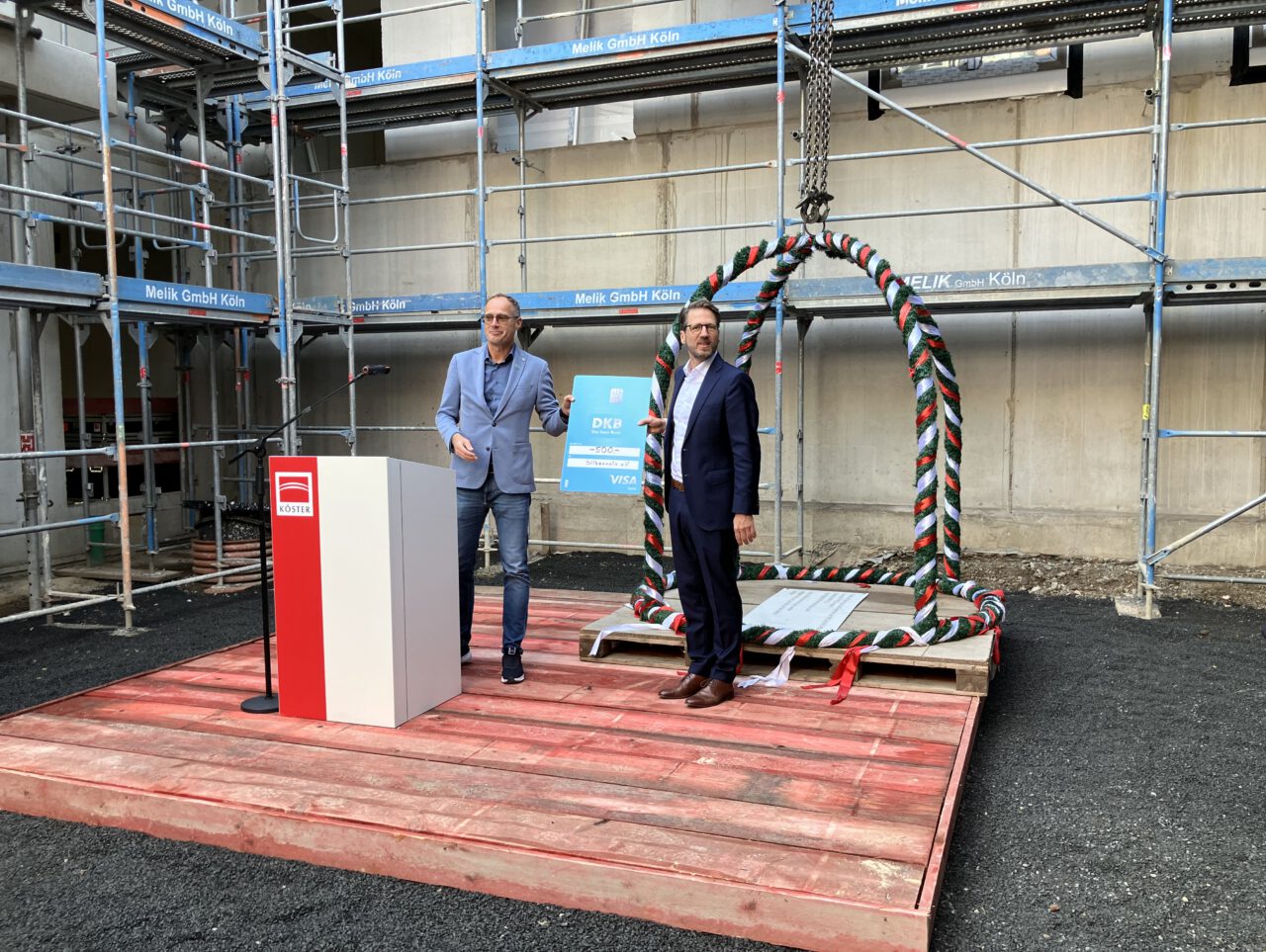 Zwei Teilnehmer bei einer Spendenübergabe auf der Baustelle des Handelshofs in Mülheim an der Ruhr während des Richtfests.
