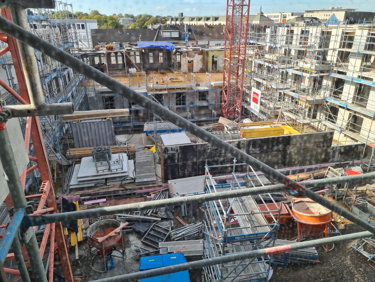 Blick von oben auf die Baustelle des Handelshofs in Mülheim an der Ruhr mit Baugerüsten, Gebäudestrukturen und einem roten Baukran.